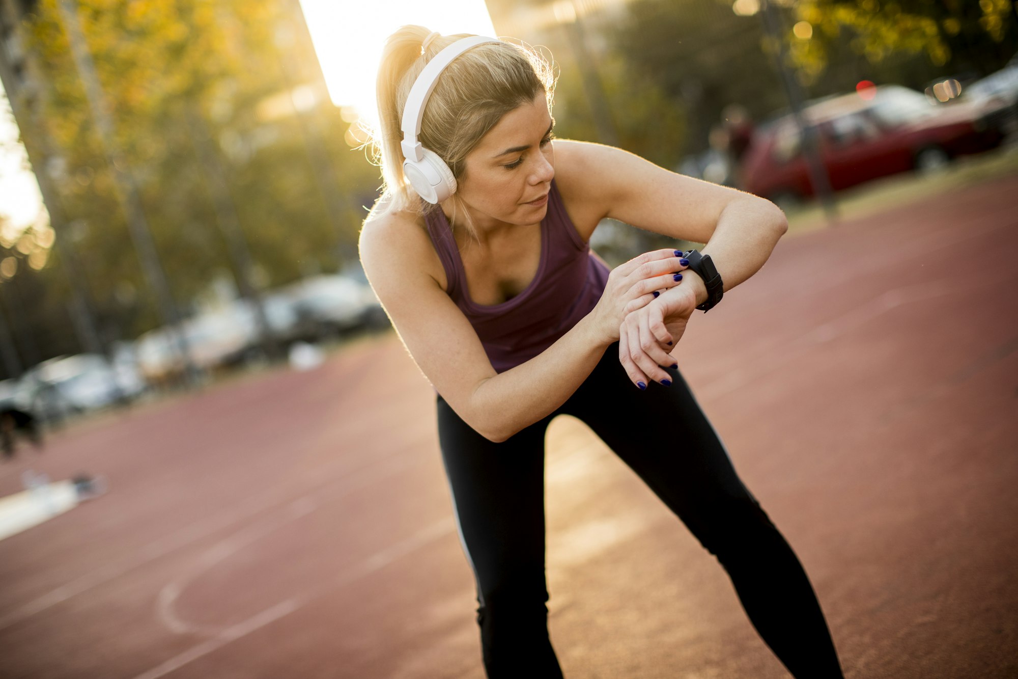 Young fitness woman looking at her smart watch while taking a break from outdoor workout