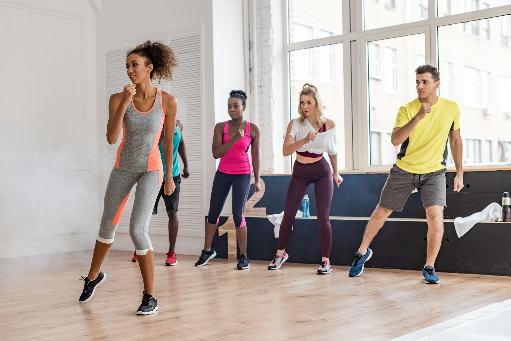 Beautiful african american trainer performing zumba movements with multicultural dancers in dance